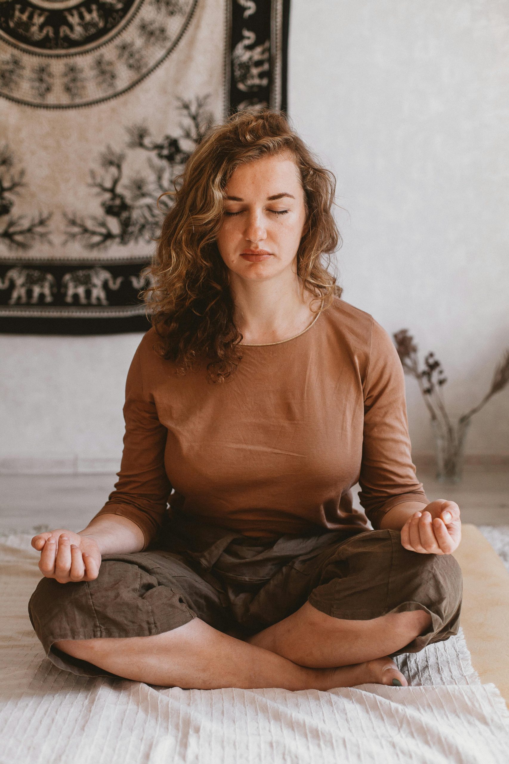 Woman meditating indoors with eyes closed, demonstrating mindful tranquility.